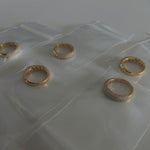 image of five gold pave rings in a jewelry bag on top of a white table