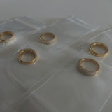 image of five gold pave rings in a jewelry bag on top of a white table