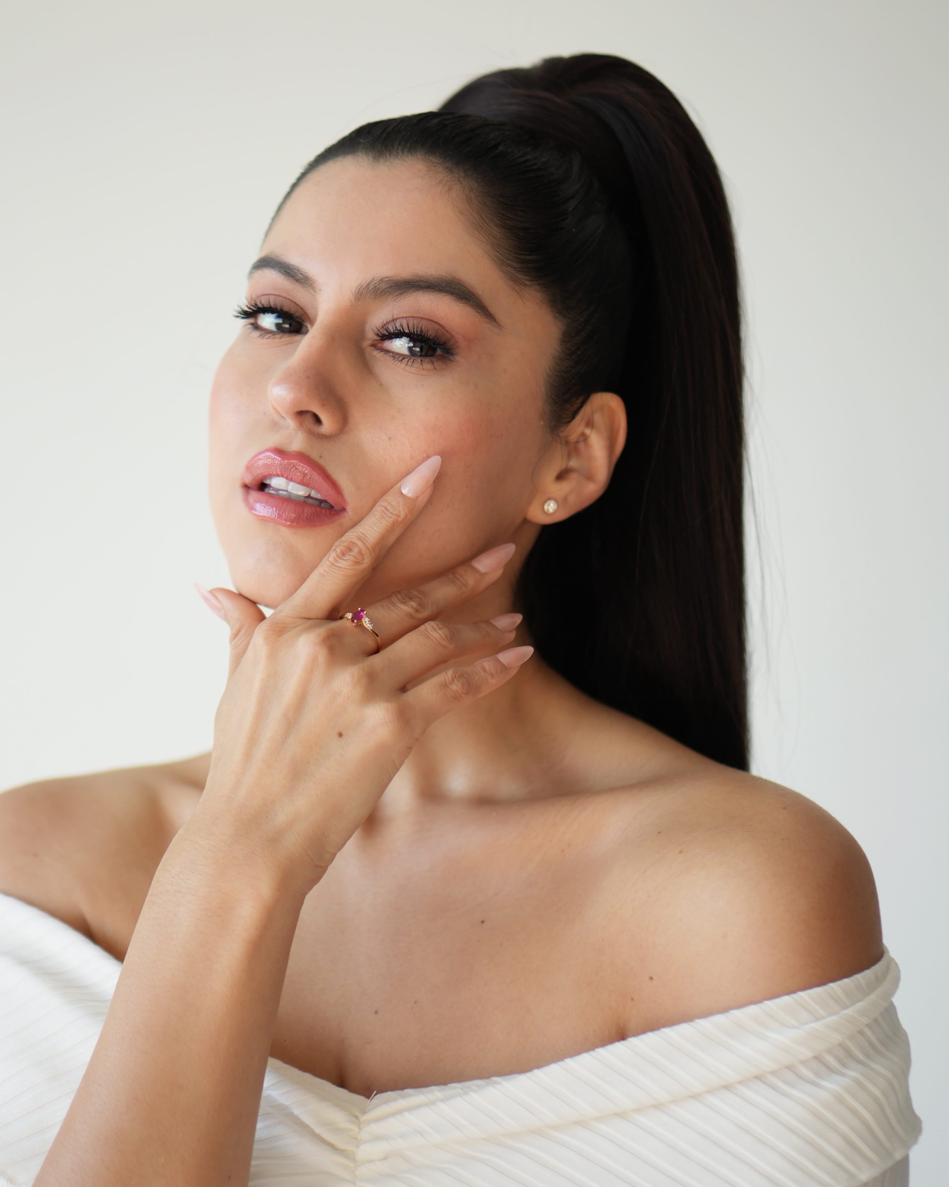 Woman in a white off-shoulder top with a plain background