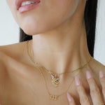Close-up of a woman wearing gold necklaces and a ring on a white background