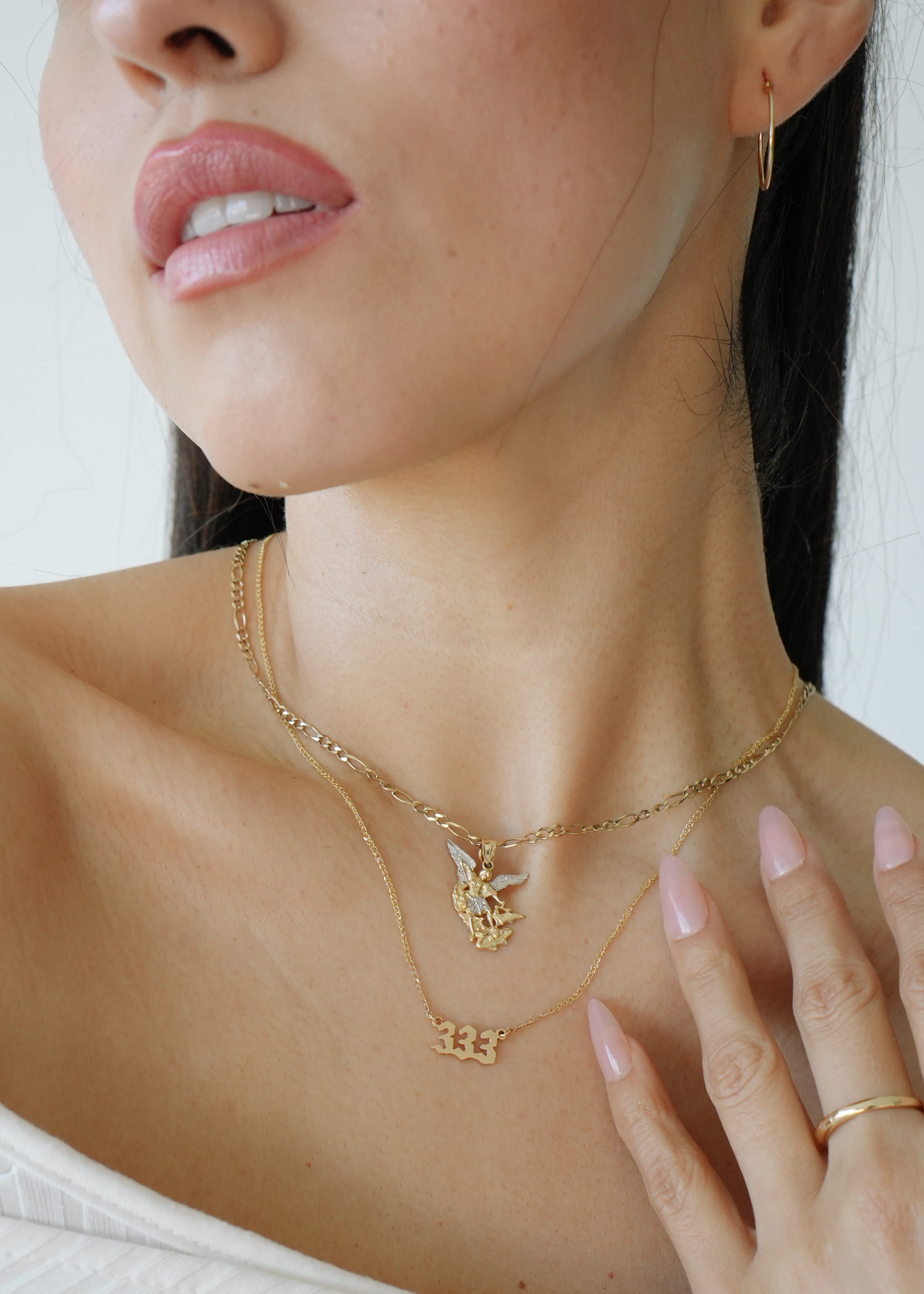 Close-up of a woman wearing gold necklaces and a ring on a white background