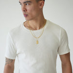 Man wearing a plain white t-shirt and black pants against a light gray background