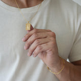 Person wearing a gold necklace and bracelet on a plain background