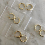 image of four pair of golden hoops in jewelry plastic bags on top of a marble table