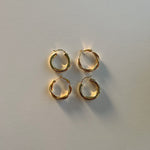 image of four gold hoop earrings on top of a white backdrop