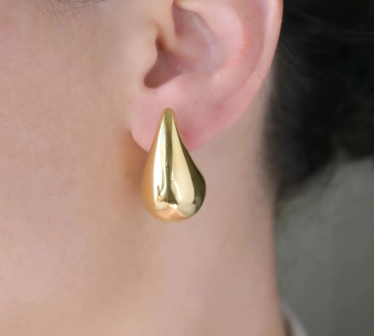 woman with large gold teardrop earrings